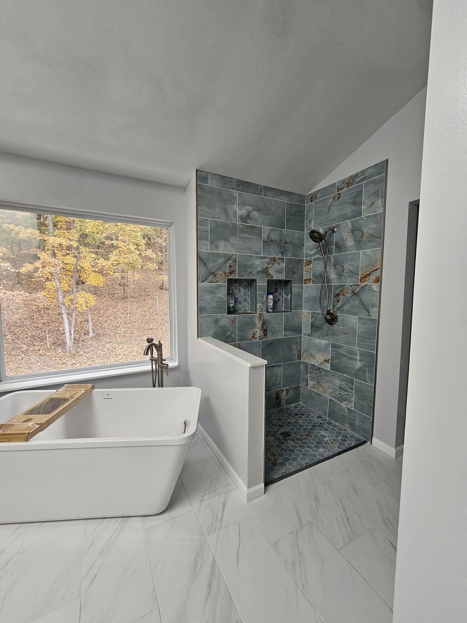 Remodeled bathroom with a freestanding tub and blue tile shower