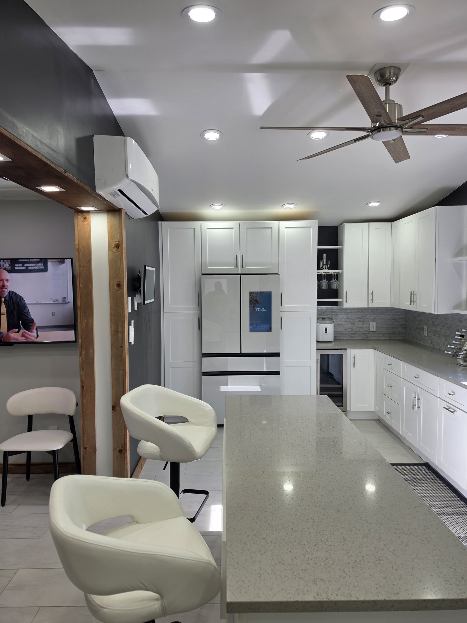 Long quartz island with bar stools facing white cabinets