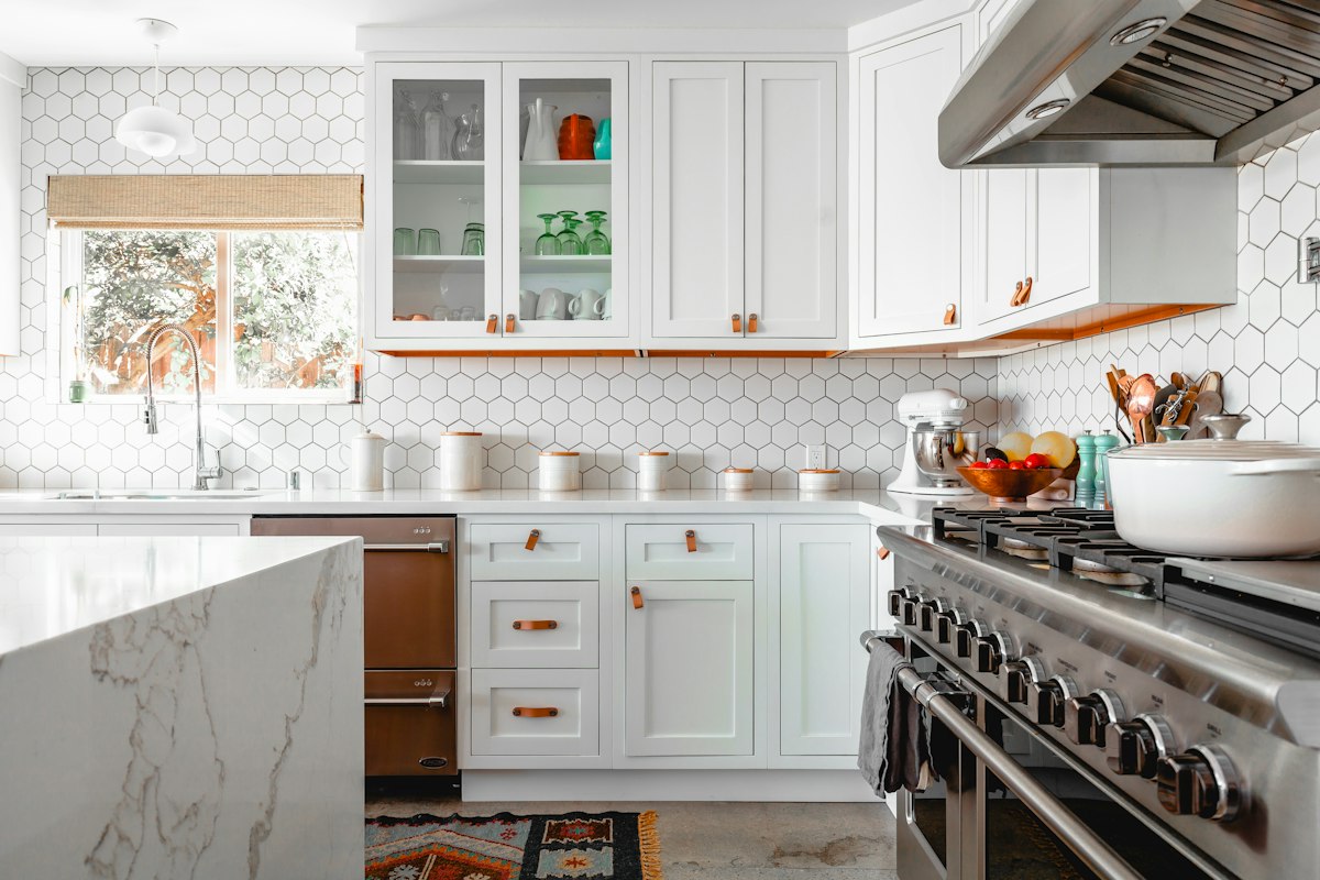 White kitchen with marble countertops and a range hood
